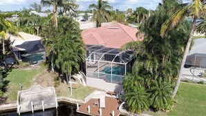 Ein Wohnhaus mit Schwimmbad, überdachter Terrasse und üppiger Bepflanzung.