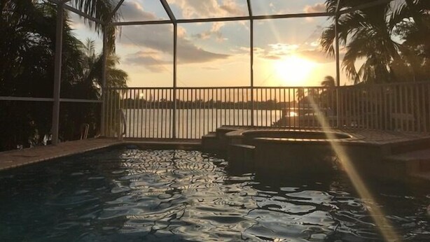 Ein Swimmingpool mit Blick auf den Sonnenuntergang und Palmen.