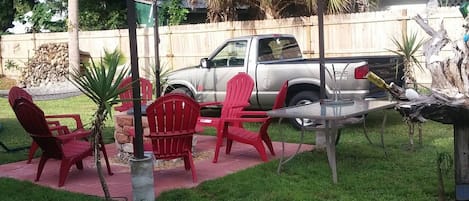 A backyard with a patio area, red chairs, a small table, and a parked truck.
