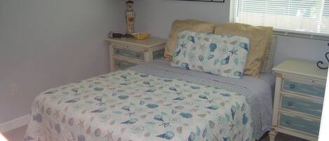 Un dormitorio con cama, mesitas de noche, lámpara y decoración en la pared.
