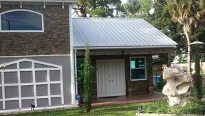 A two-story house with a stone facade, a garage, and a metal roof. - Private guesthouse near the beach (Sarasota)