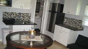 A compact kitchen with a dining area, including a round table with chairs, a microwave, a refrigerator, and a sink. - Private guesthouse near the beach (Sarasota)