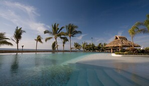 Una piscina azul cristalina con palmeras y una estructura de techo de paja.