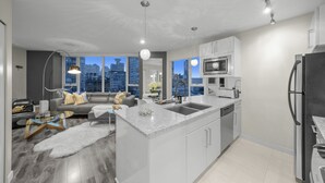 A modern kitchen with a large island, stainless steel appliances, and a city view. - Stunning modern luxury 2 bedroom, 2 bath condo rental  (Vancouver)