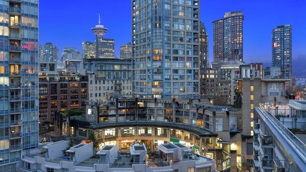 A high-rise urban hotel with multiple floors, large windows, and a prominent tower in the background. - Stunning modern luxury 2 bedroom, 2 bath condo rental  (Vancouver)