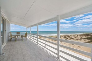 A covered outdoor area with a wooden deck, white railings, and a view of the beach. - 405 Ocean-Front with Panoramic Ocean Views (Nags Head)