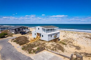 A beachfront property with a two-story house, a covered porch, and a sandy beach area. - 405 Ocean-Front with Panoramic Ocean Views (Nags Head)