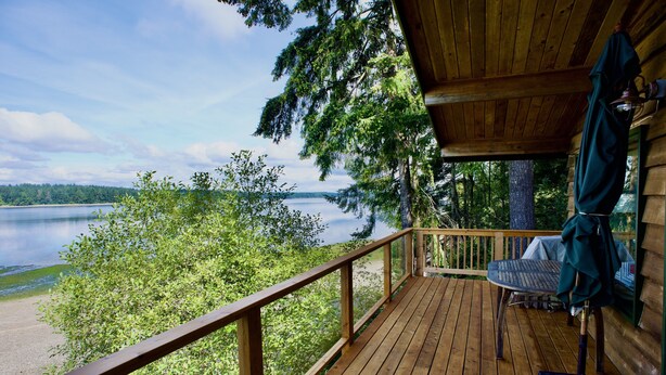 Eine Holzterrasse mit Blick auf einen See und einen Wald.