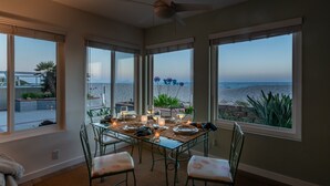 Espaço de refeições com mesa posta para quatro pessoas, com vista para a praia.