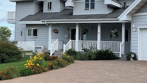 Ein zweistöckiges Haus mit Veranda, Garage und einem bepflanzten Garten mit Blumen.