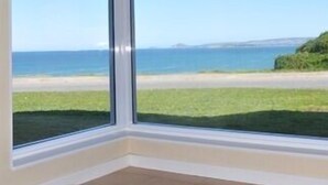 Habitació amb grans finestres que donen vista a la platja i a l'oceà.