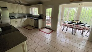 A kitchen with white cabinets, a dishwasher, and a dining area with a table and chairs.
