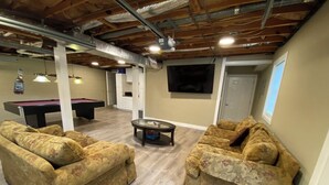 A living room with two floral-patterned sofas, a pool table, and a billiards table.
