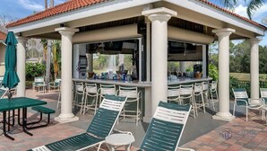 A covered outdoor bar area with a grill, seating, and a view of the surrounding landscape. - Emerald Island - 3BR, 2BA townhome in gated resort (Kissimmee)