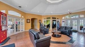 A spacious lobby with leather sofas, a coffee table, and a children's play area with a ticket booth. - Emerald Island - 3BR, 2BA townhome in gated resort (Kissimmee)