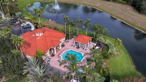 A large house with a red roof, a swimming pool, and a pond with a fountain. - Emerald Island - 3BR, 2BA townhome in gated resort (Kissimmee)