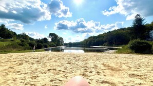 Une plage de sable avec un lac et des arbres en arrière-plan.