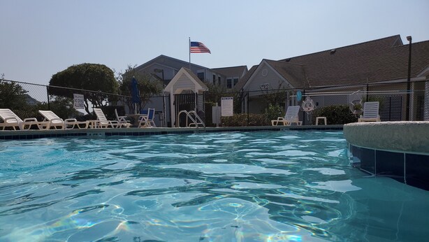 Kirkasvetinen uima-allas, aurinkotuoleja ja pieni rakennus, jonka edessä liehuu Yhdysvaltain lippu.