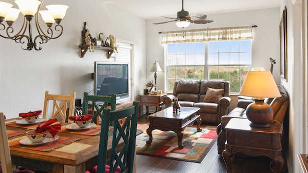 Un salon comprenant un coin repas, un ventilateur de plafond, un téléviseur et une fenêtre donnant sur un paysage agréable.