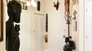 Un couloir avec des portes blanches, un tapis à motifs et diverses sculptures et décorations murales.