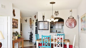 Un coin repas avec une table et des chaises en bois, un lustre et divers éléments de décoration murale, notamment des têtes d’animaux et une horloge.