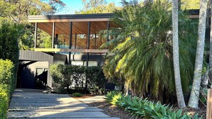 A modern building with a wooden deck and a pathway leading to a covered area. - Private Architectual Beach Retreat in Pearl Beach (pearl beach)