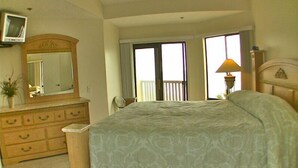 Une chambre à coucher avec un lit, une commode, un miroir et un balcon offrant une vue.