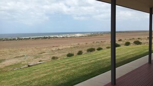 Un espacio al aire libre techado con vista al océano y un paisaje con césped.