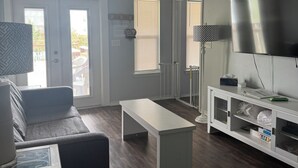 Een woonkamer met een bank, een salontafel, een televisie en een plafondventilator.
