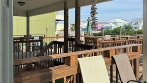 Een overdekt terras met houten tafels en stoelen, een hanglamp en een uitzicht op kleurrijke gebouwen op de achtergrond.