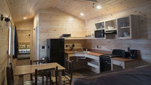 Eine gemütliche Holzhütte mit Küchenzeile, Esstisch und Stühlen.
