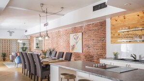 Een moderne keuken met een bakstenen muur, een eethoek met stoelen en een bar met planken.