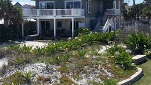 A two-story house with a balcony, a covered porch, and a staircase leading to the upper floor. - Oceanfront Home- Casa Del Sol- Live the LIFE!  4 decks, beach gear, grill... (St Augustine Beach)