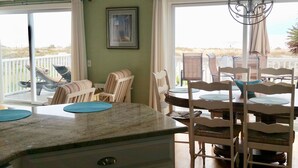 A dining area with a table and chairs, a chandelier, and a view of the outdoors. - Oceanfront Home- Casa Del Sol- Live the LIFE!  4 decks, beach gear, grill... (St Augustine Beach)