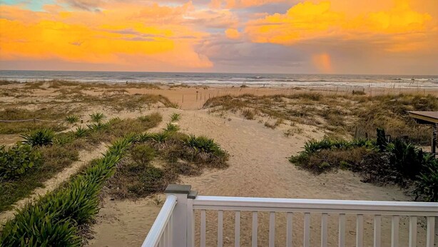 A beach view with a wooden walkway leading to the ocean, surrounded by dunes and vegetation. - Oceanfront Home- Casa Del Sol- Live the LIFE!  4 decks, beach gear, grill... (St Augustine Beach)