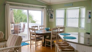 A dining area with a table set for four, surrounded by chairs. There is a sliding glass door leading to an outdoor patio area. - Oceanfront Home- Casa Del Sol- Live the LIFE!  4 decks, beach gear, grill... (St Augustine Beach)