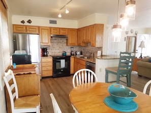 A modern kitchen with wooden cabinets, stainless steel appliances, and a dining area with a wooden table and chairs.
