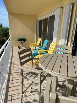Un balcon doté d’un espace extérieur aménagé avec des chaises et une table, ainsi qu ’un barbecue.