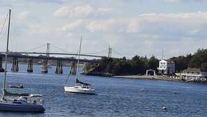 A waterfront scene with a bridge, sailboats, and a building with a white facade.