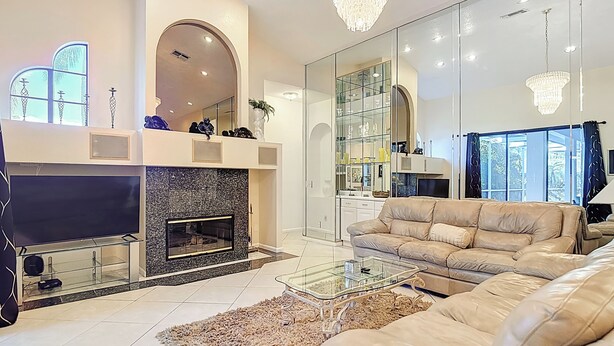 Ein modernes Wohnzimmer mit Kamin, Ledersofa, Glastisch und einer Kristallleuchtre.