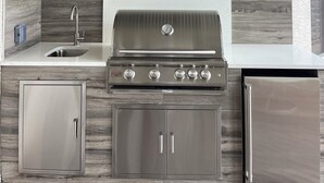 Una cocina moderna con estufa a gas integrada, gabinetes de acero inoxidable y una campana extractora grande sobre la cocina.