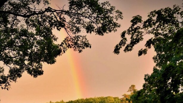 A serene lakeside scene with boats docked and a rainbow in the background. - Waterfront Cottage in South Bristol w/ private dock and lobster boat views (South Bristol)