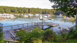A marina with docked boats, a wooden pier, and surrounding greenery. - Waterfront Cottage in South Bristol w/ private dock and lobster boat views (South Bristol)