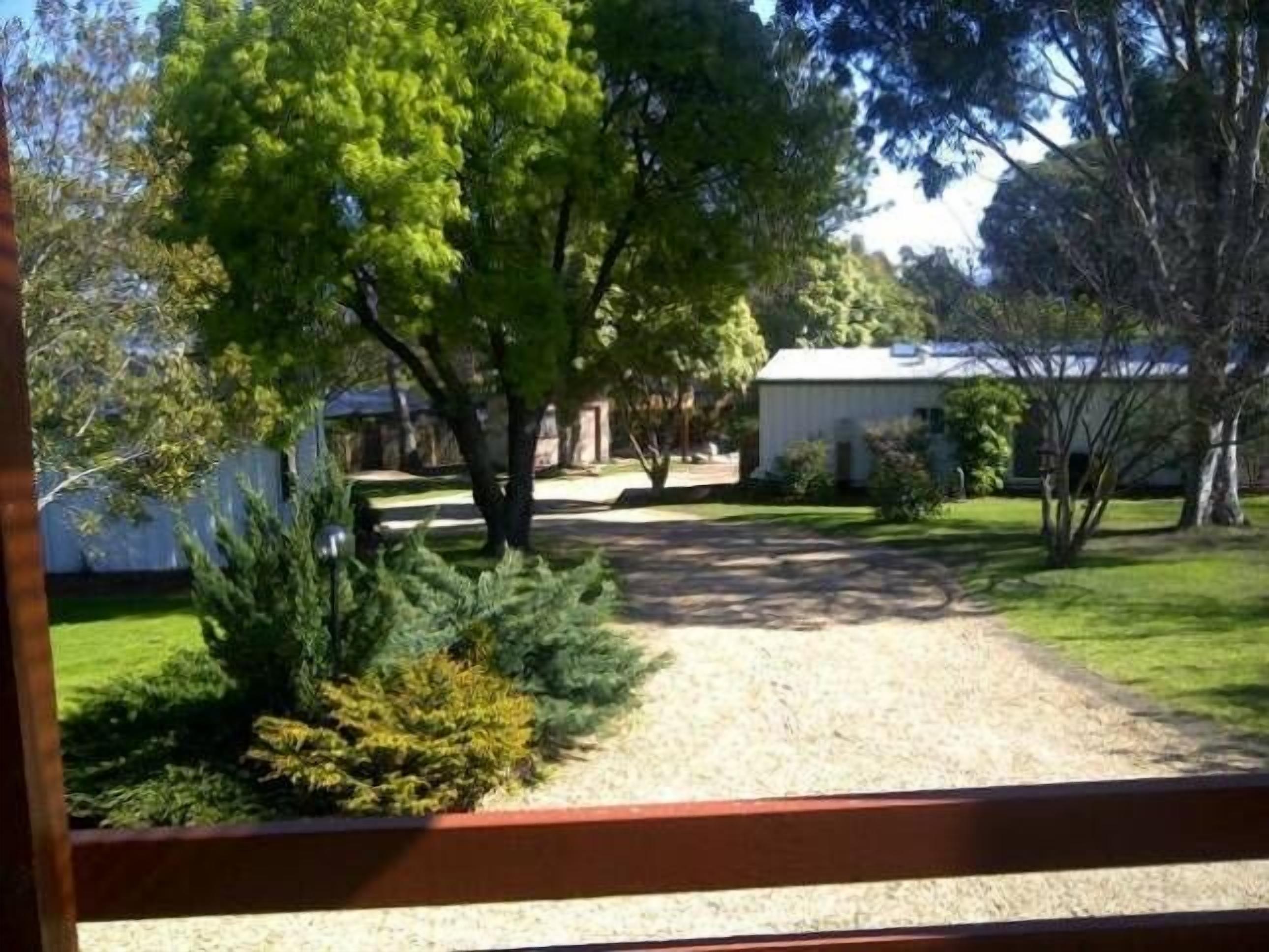 Una propiedad residencial con camino de grava, césped y una pequeña construcción de fachada blanca.