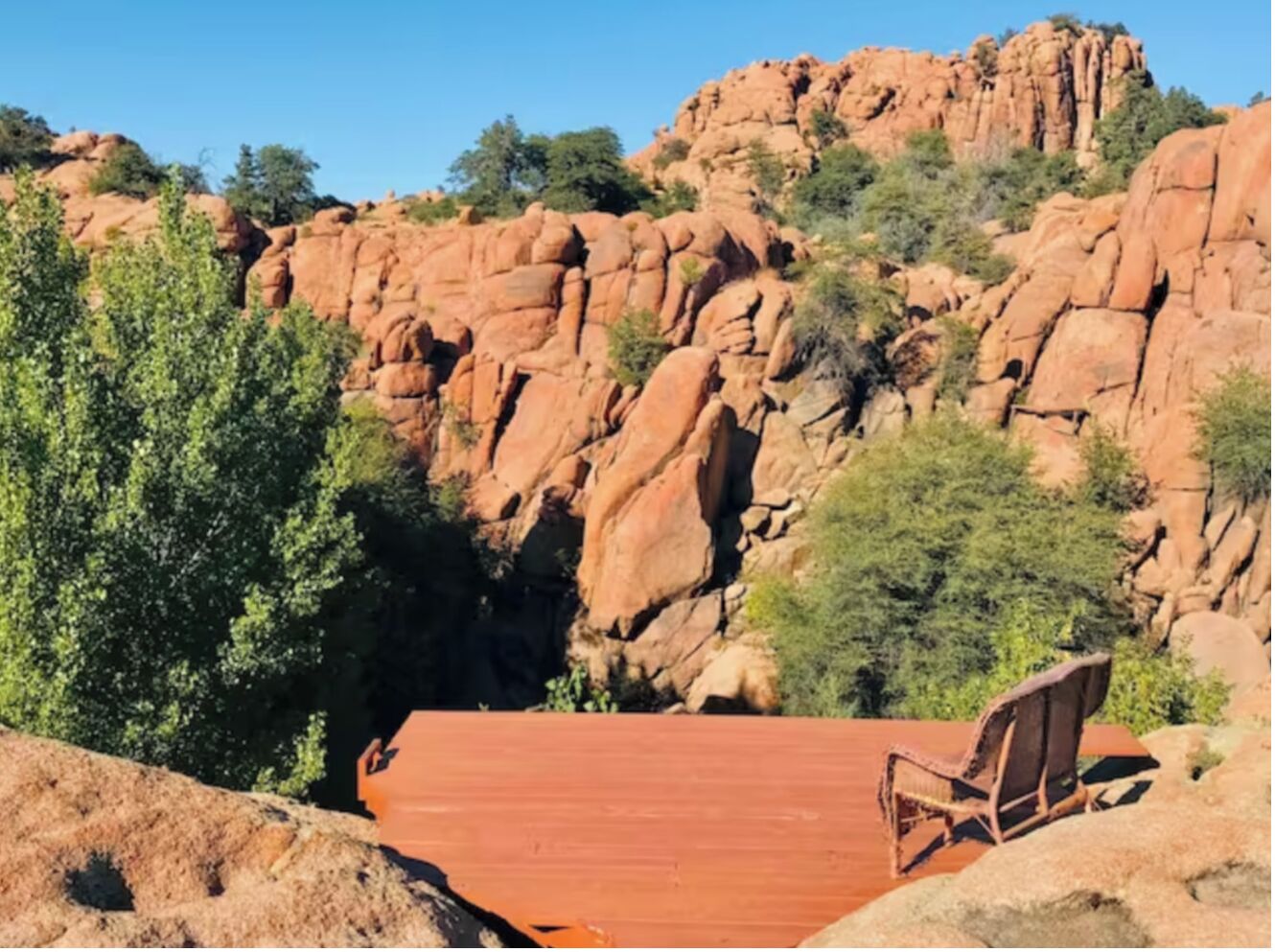 A red rock formation with a wooden chair in the foreground.