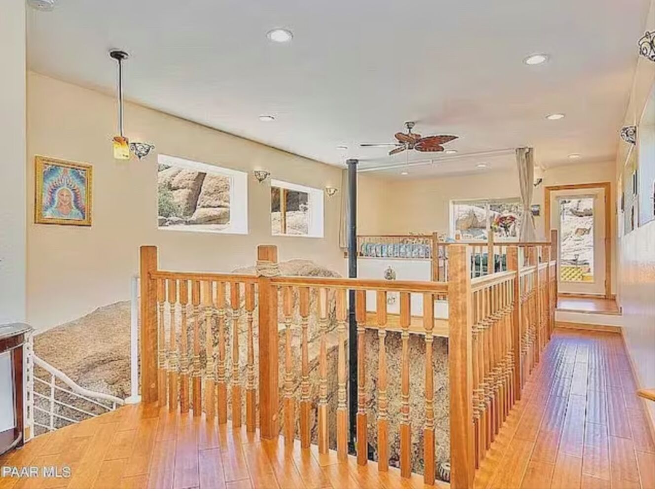 Une pièce spacieuse avec un escalier en bois, un ventilateur de plafond et une vue sur l’extérieur.