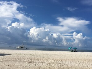 Una playa con un bote, sombrillas y cielo despejado.