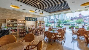 Un interior moderno con muebles de madera, una recepción visible y grandes ventanales que ofrecen vistas a un edificio tradicional.
