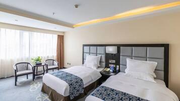 A hotel room with two beds, a nightstand, a lamp, a chair, and a window with curtains.