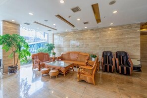 En lobby med sofa, stole, sofabord og en potteplante.